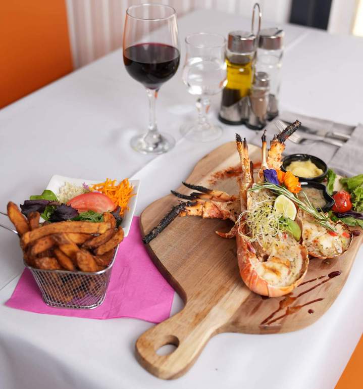Plateau de langoustes grillées, servi avec des sauces, une salade fraîche, des frites et un verre de vin Martinique