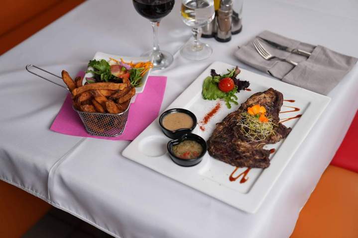 Entrecôte grillée, servie avec des frites, des sauces et de salades Martinique